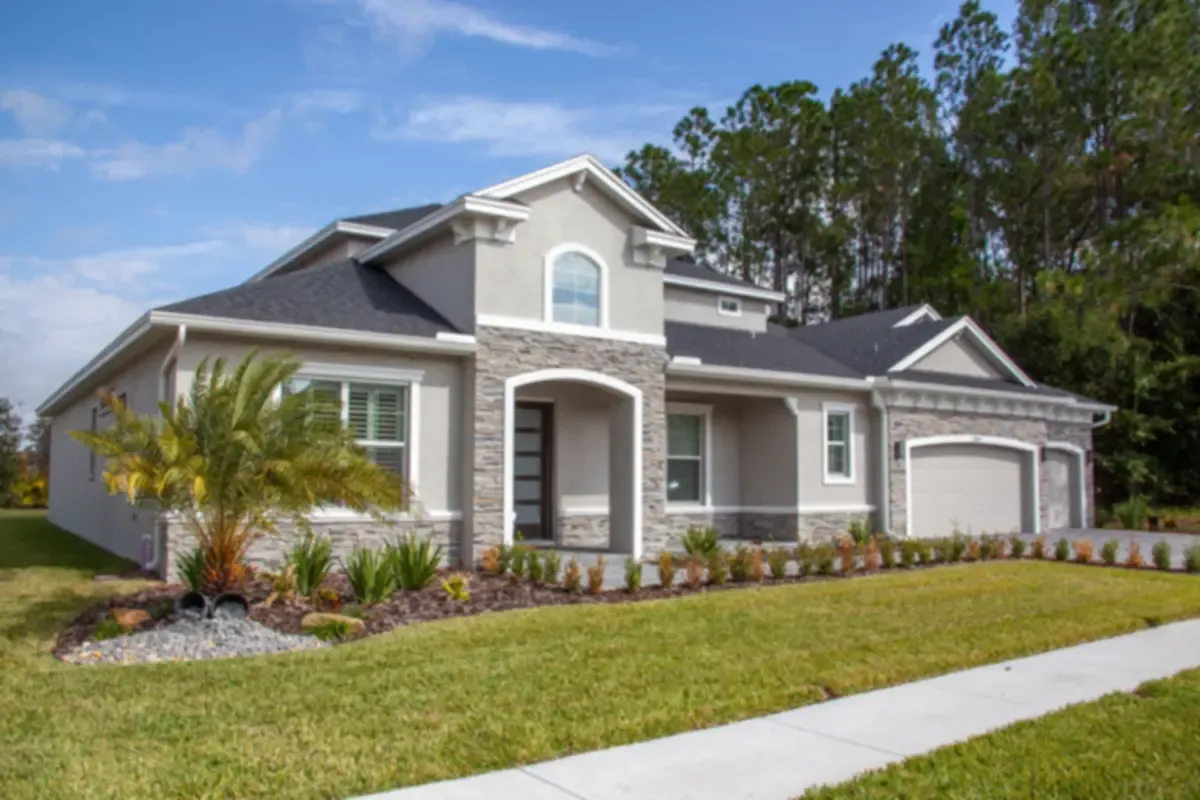 New two-story stucco and stone home with a landscaped yard and a palm on a sunny day